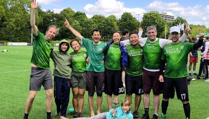 A picture of Ultimate frisbee players posing with a trophy after winning the Netherlands outdoor competition.